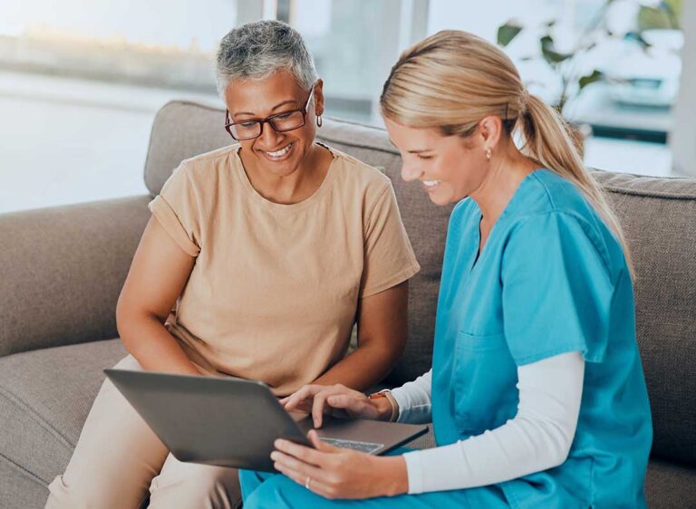 A senior resident uses a call button while a staff member responds in a well-lit common area.